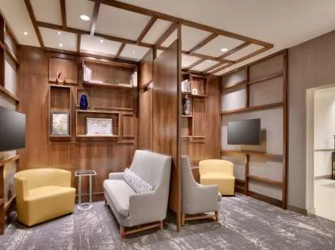 Hyatt Place media pod seating area with wood shelving and armchairs